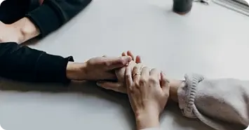 Two people holding hands over a desk